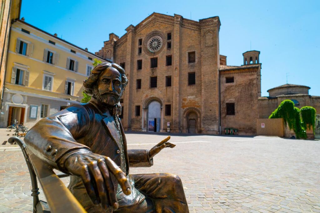 Statua di Giuseppe Verdi in Piazzale San Francesco con veduta alle spalle di San Francesco del prato